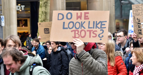 woman holding cardboard box with do we look like bots ? text