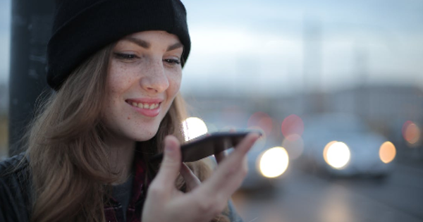 Joyful young woman phoning on street in evening