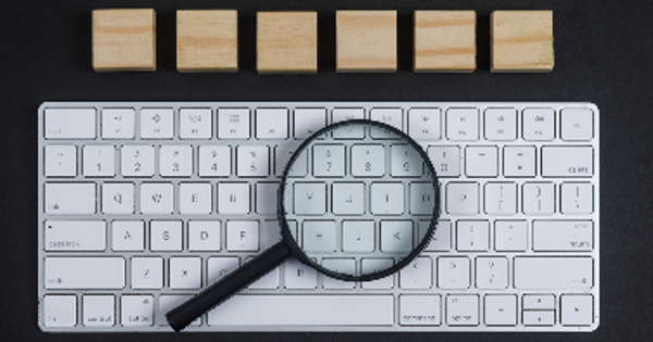 Keyboard, magnifier, wooden cubes on black desk background