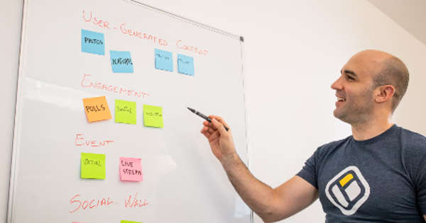 a man writing on a white board with sticky notes on it