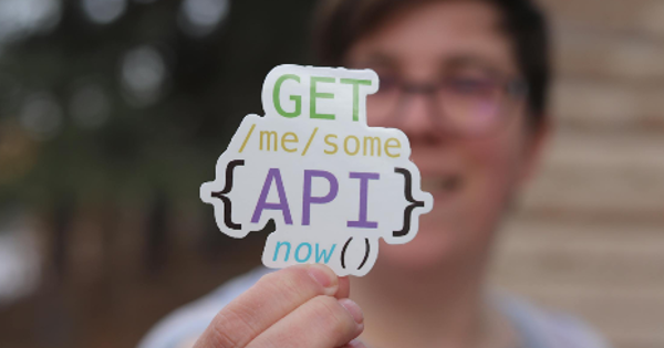 Programmer Holding a Paper Cutout with an API Quote