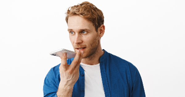 Redhead man record voice message, holding smartphone near lips