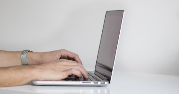 User typing on laptop in front of white background