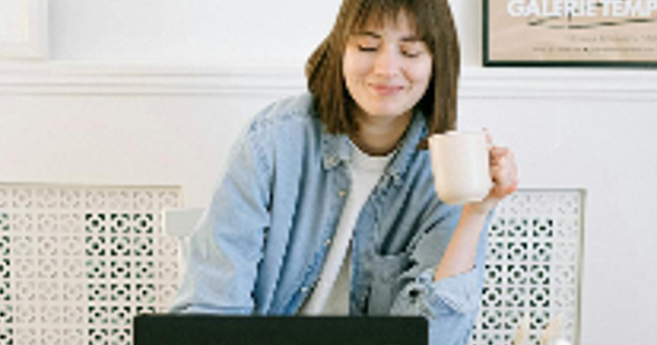 Woman Drinking Coffee and Looking at a Laptop