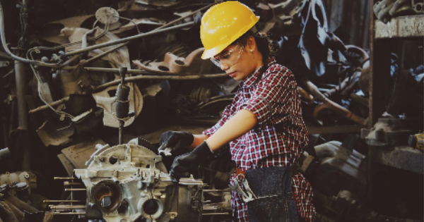 Woman Wears Yellow Hard Hat Holding Vehicle Part