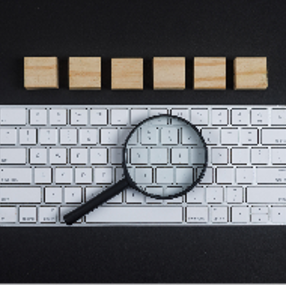 Keyboard, magnifier, wooden cubes on black desk background