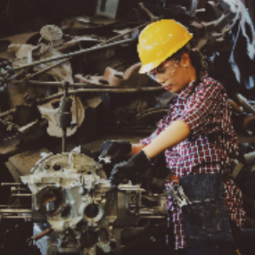 Woman Wears Yellow Hard Hat Holding Vehicle Part